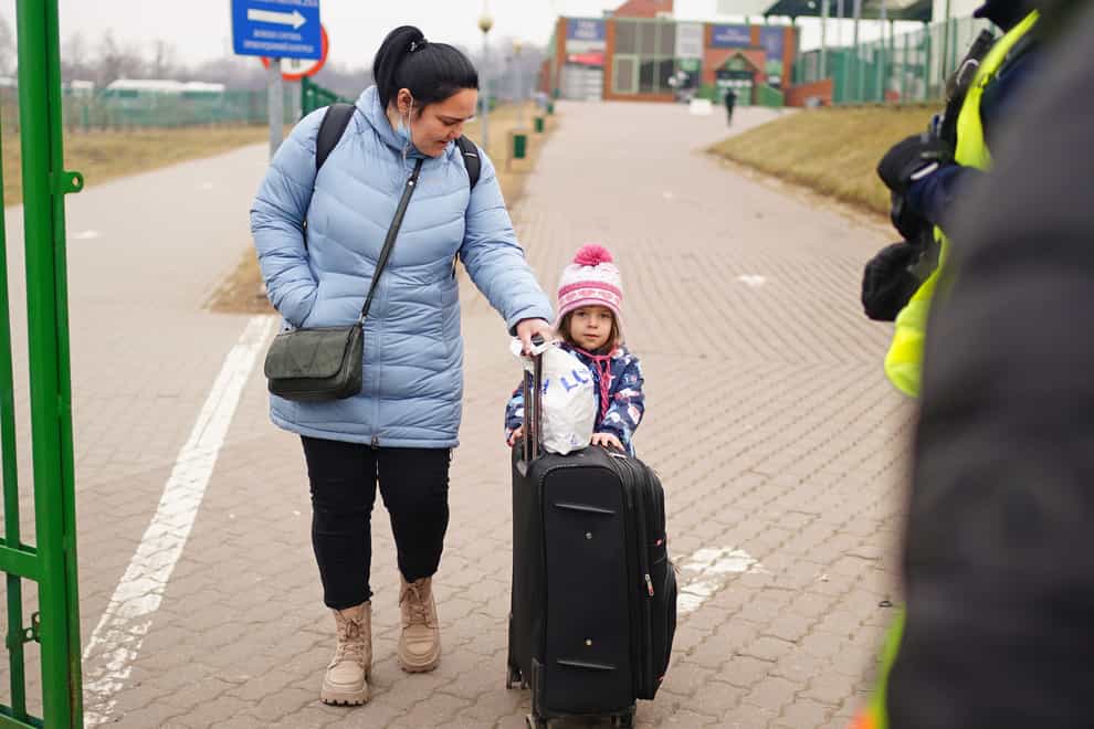 A family cross the border point from Ukraine into Medyka, Poland (Victoria Jones/PA)