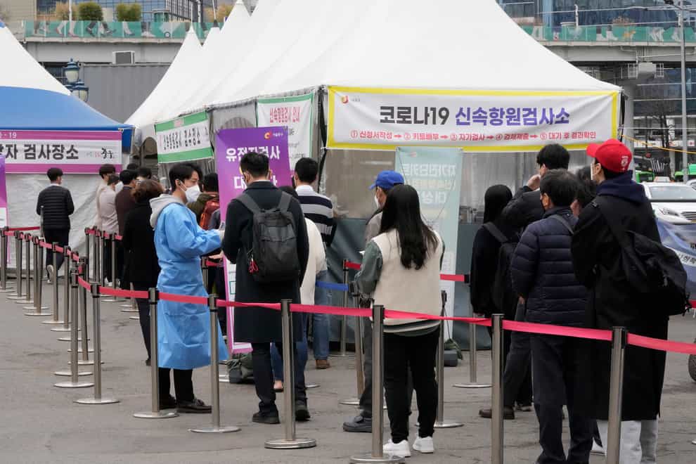 A medical worker guides people waiting for a coronavirus test at a makeshift site in Seoul, South Korea (Ahn Young-joon/AP)