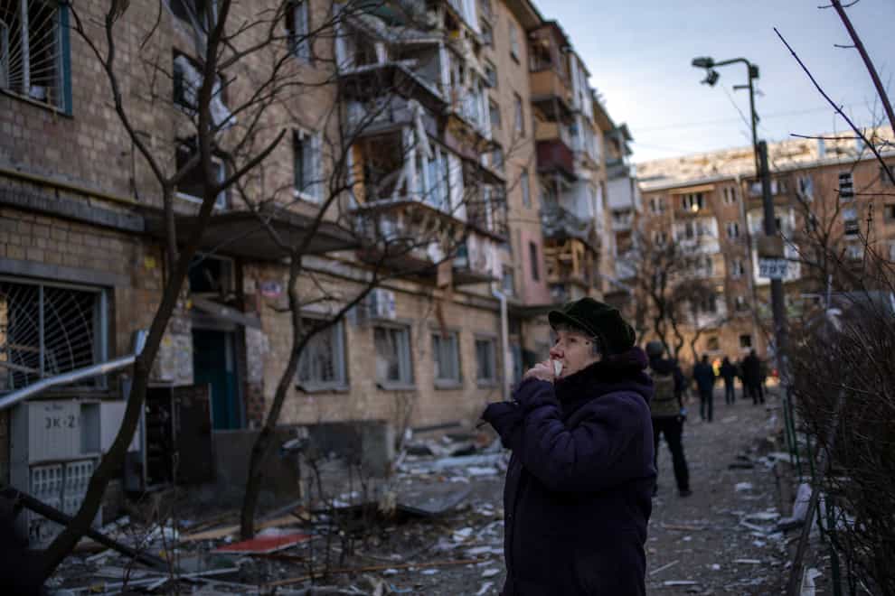 A woman looks at residential buildings damaged by a bomb in Kyiv, Ukraine, on Friday March 18 2022 (Rodrigo Abd/AP)
