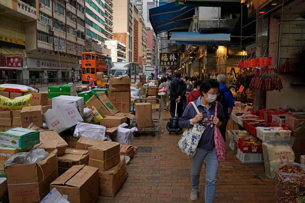 A woman wearing a face mask walks at a local market in Hong Kong (Kin Cheung/AP)