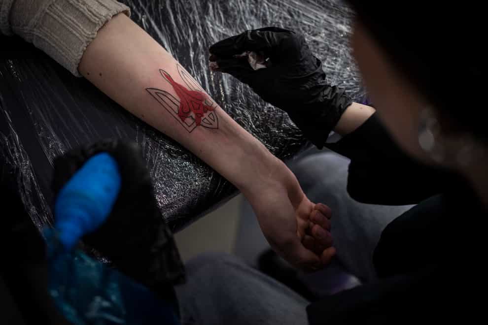 Ukrainian Natalia Tanchynets works on a patriotic-themed tattoo at her workshop in Lviv, Western Ukraine (Bernat Armangue/AP)
