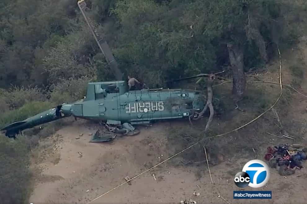 This aerial video image shows emergency personnel next to a Los Angeles Sheriff Department helicopter after it crashed in California (ABC7 Los Angeles via AP)