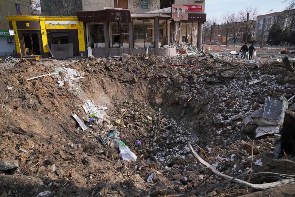 People walk past a crater from the explosion in Mira Avenue (Avenue of Peace) in Mariupol, Ukraine (Evgeniy Maloletka/AP)
