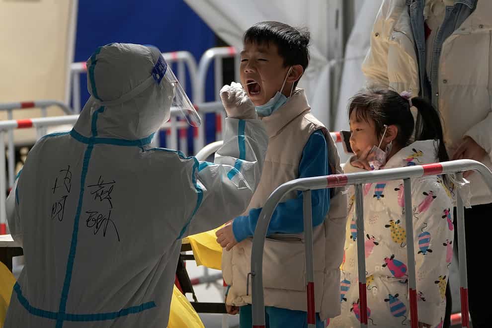 A health worker in a protective suit takes a throat swab sample from a child at a coronavirus testing site in Beijing, China (Andy Wong/AP)