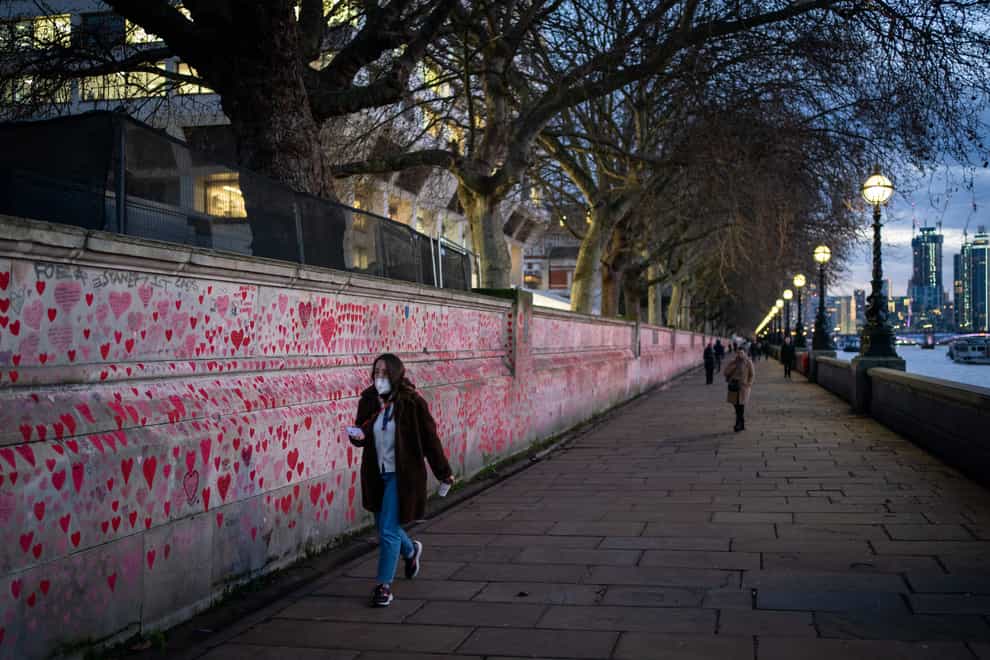 A woman passes the Covid memorial wall in London (Dominic Lipinski/PA)