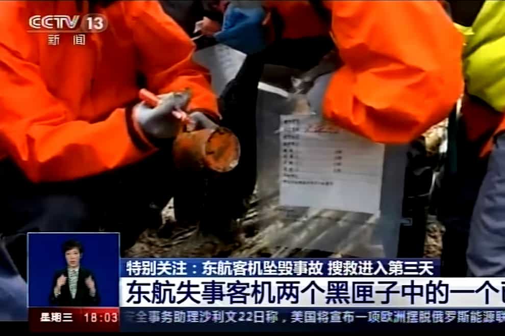 An emergency worker holding an orange-coloured ‘black box’ recorder found at the China Eastern flight crash site (CCTV via AP Video)
