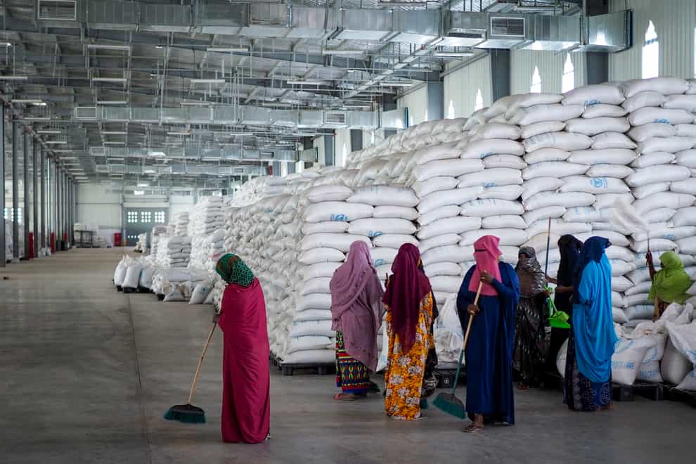Workers clean the floor as sacks of food earmarked for the Tigray and Afar regions sit in piles in a warehouse of the World Food Programme (AP)