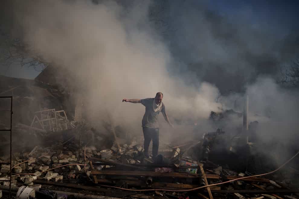 A man walks on the debris of a burning house in Kharkiv, Ukraine (Felipe Dana/AP)