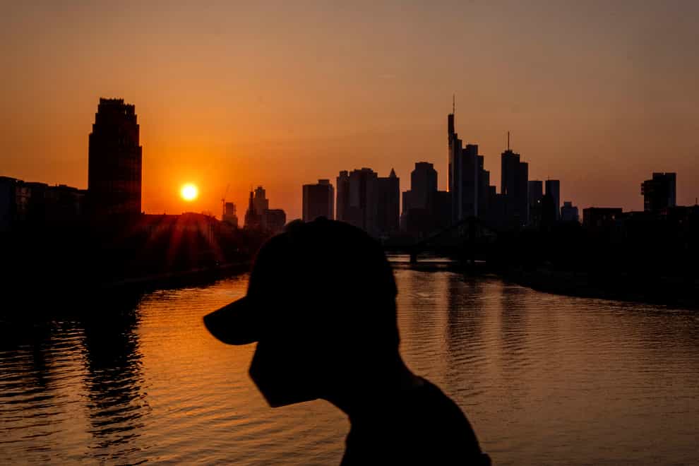 A man wears a face mask as he walks on a bridge over the river Main as the sun sets in Frankfurt (Michael Probst/AP)