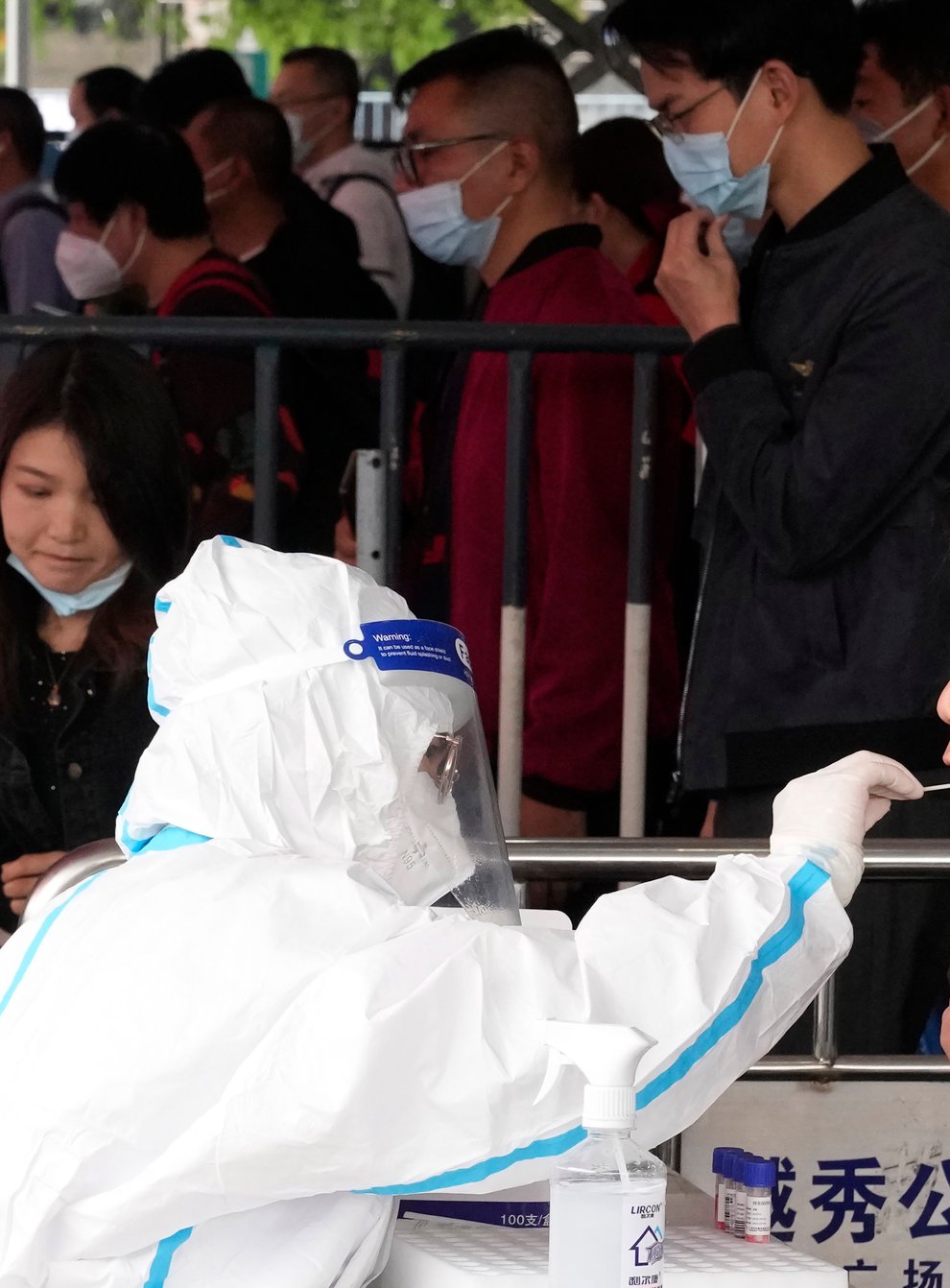 A worker takes a swab from a passenger for a Covid-19 test at the Guangzhou train station (Ng Han Guan/AP)