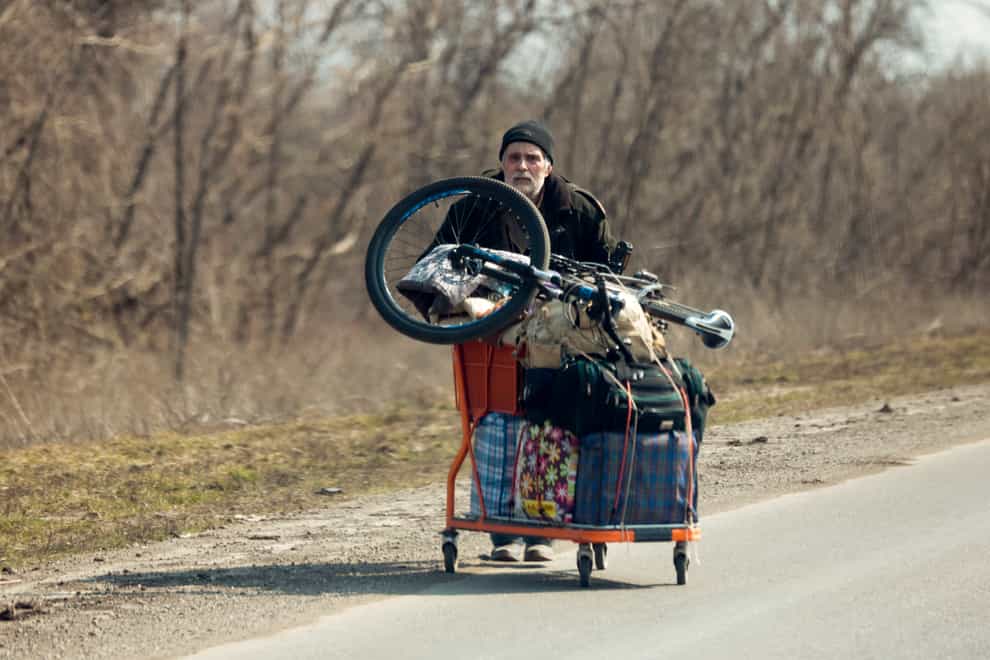 A local resident pushes a supermarket cart with his belongings as he flees Mariupol (Alexei Alexandrov/AP)