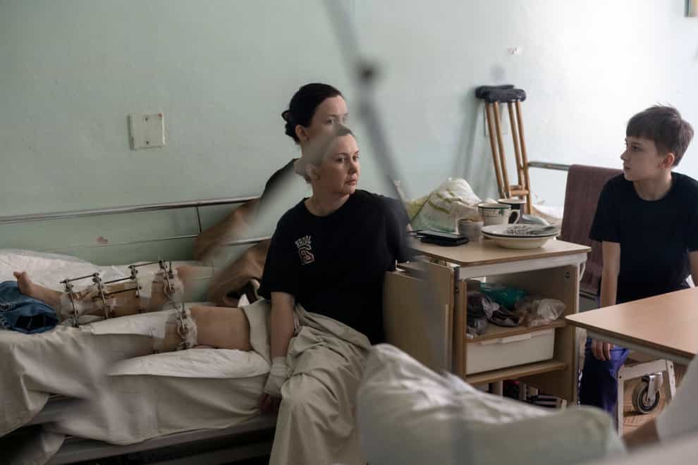 Natalya Vakula, 44, rests in a hospital in Brovary, on the outskirts of Kyiv, next to her son Dima 11, while recovering from injuries in her leg after a Russian attack in Chernihiv (AP)