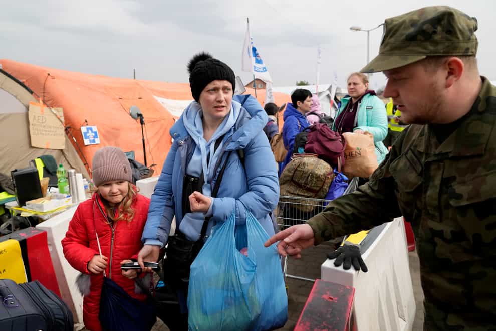 A Polish soldier directs refugees as they wait in a queue with their belongings after fleeing the war from neighbouring Ukraine at the border crossing in Medyka, southeastern Poland, on Tuesday, March 29, 2022. The daily number of people fleeing Ukraine has fallen in recent days but border guards, aid agencies and refugees say Russia’s unpredictable war offers few signs whether it’s just a temporary lull or a permanent drop-off. (AP Photo/Sergei Grits)