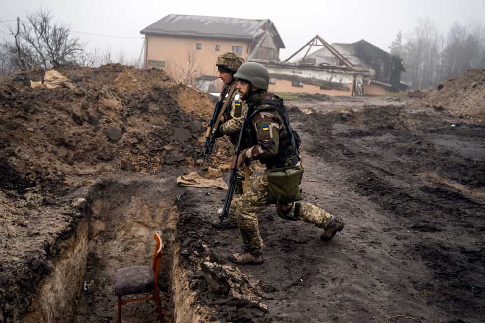 Ukrainian soldiers approach a trench that had been used by Russian soldiers as they retake an area on the outskirts of Kyiv, Ukraine, Friday, April 1, 2022. (AP Photo/Rodrigo Abd)