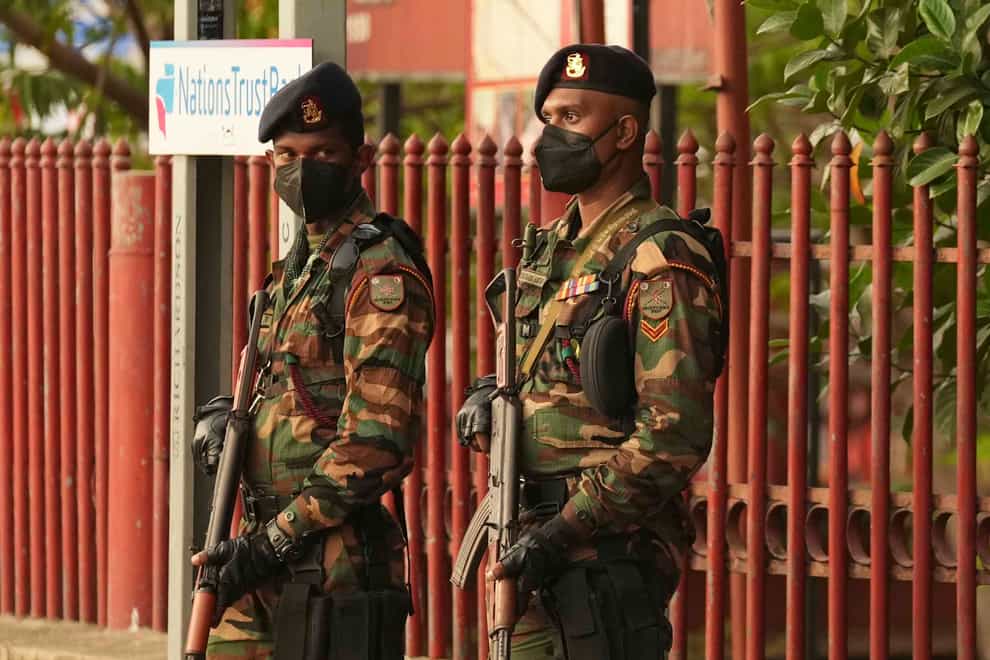 Sri Lankan soldiers stand guard before the curfew begins in Colombo (Eranga Jayawardena/AP)