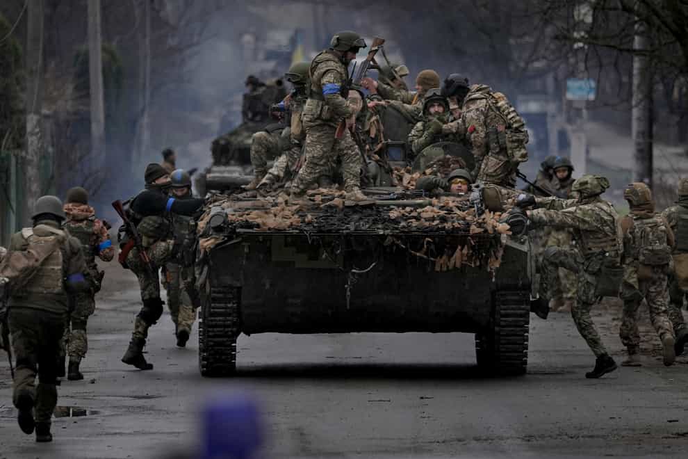 Ukrainian servicemen climb on a fighting vehicle outside Kyiv (Vadim Ghirda/AP)