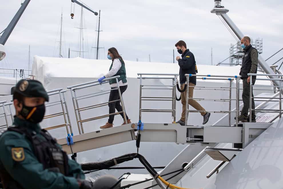 A US federal agent and two Civil Guards board the yacht called Tango in Palma de Mallorca, Spain, on Monday April 4 2022 (Francisco Ubilla/AP)