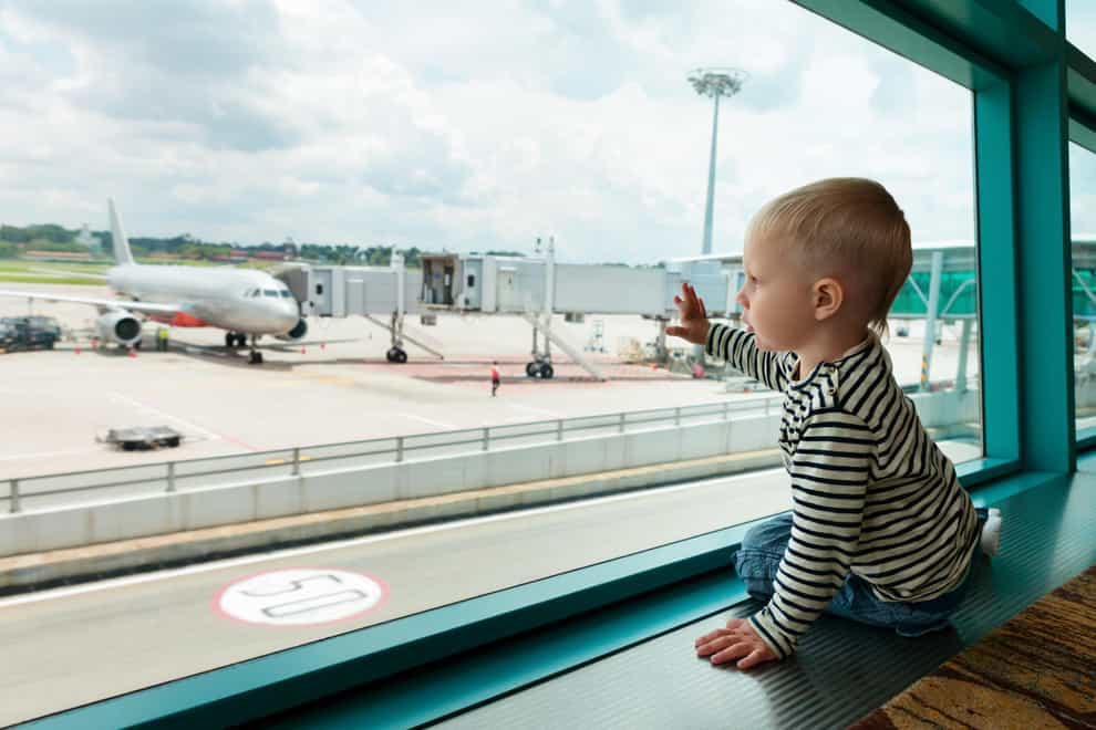 Little baby boy waiting boarding to flight in airport transit hall and looking through the window at airplane near departure gate (Alamy/PA)