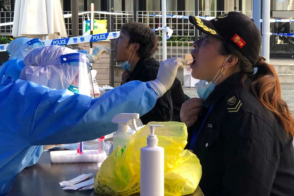 A medical worker collects sample swab sample from residents in a lockdown area in the Jingan district of western Shanghai, Monday, April 4, 2022. China has sent more than 10,000 health workers from across the country to Shanghai, including 2,000 military medical staff, as it struggles to stamp out a rapidly spreading COVID-19 outbreak in China’s largest city. (AP Photo/Chen Si)