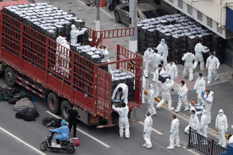 Workers in PPE unload groceries from a truck before distributing them to local residents under the COVID-19 lockdown in Shanghai, China (Chinatopix/AP)