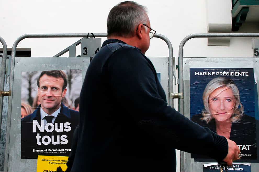 A man walks past presidential campaign posters of french president Emmanuel Macron and centrist candidate for reelection and french far-right presidential candidate Marine Le Pen in Anglet, southwestern France, Wednesday, April 8, 2022. France’s first round of the presidential election takes place on April 10, with a presidential runoff on April 24 if no candidate wins outright. (AP Photo/Bob Edme)