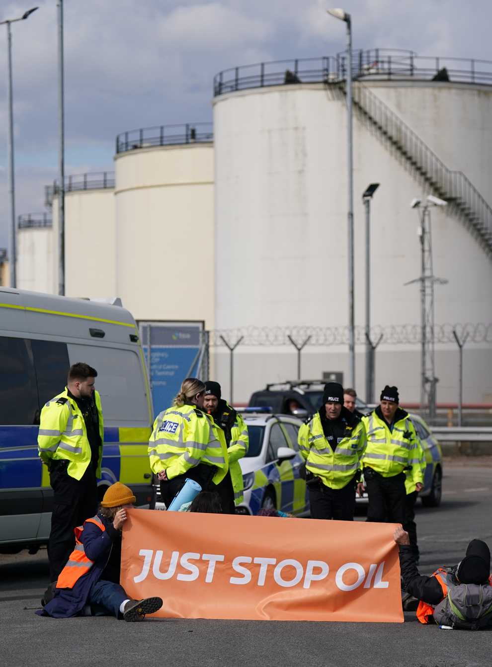 Police officers look at activists from Just Stop Oil taking part in a blockade at the Kingsbury Oil Terminal, Warwickshire (PA)