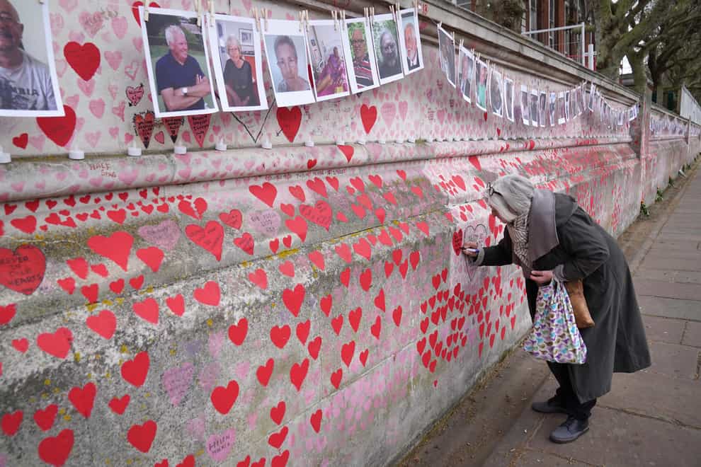 Photographs on the Covid memorial wall in London (Stefan Rousseau/PA)