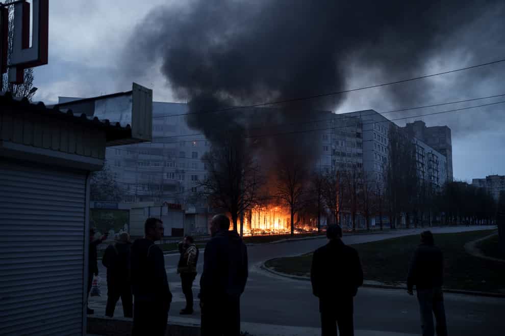 Residents stand outside their apartments as shops burn after a Russian attack in Kharkiv, Ukraine (AP)