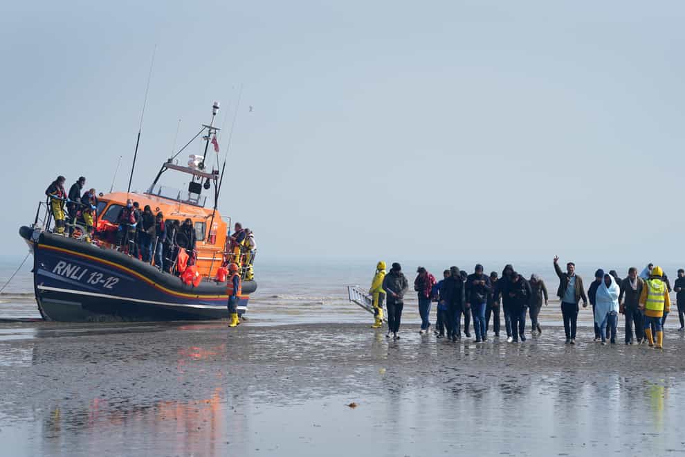 A group of people are guided up the beach after being brought into Dungeness, Kent, onboard the RNLI Lifeboat following a small boat incident in the Channel (Gareth Fuller/PA)