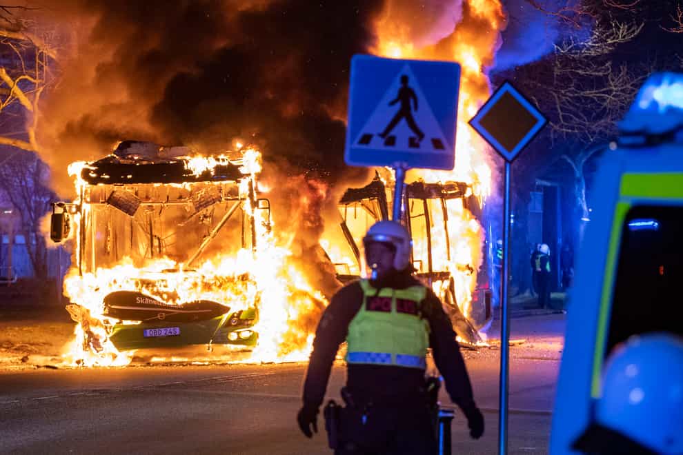 Riot police watch a city bus burn on a street in Malmo (Johan Nilsson/TT via AP)