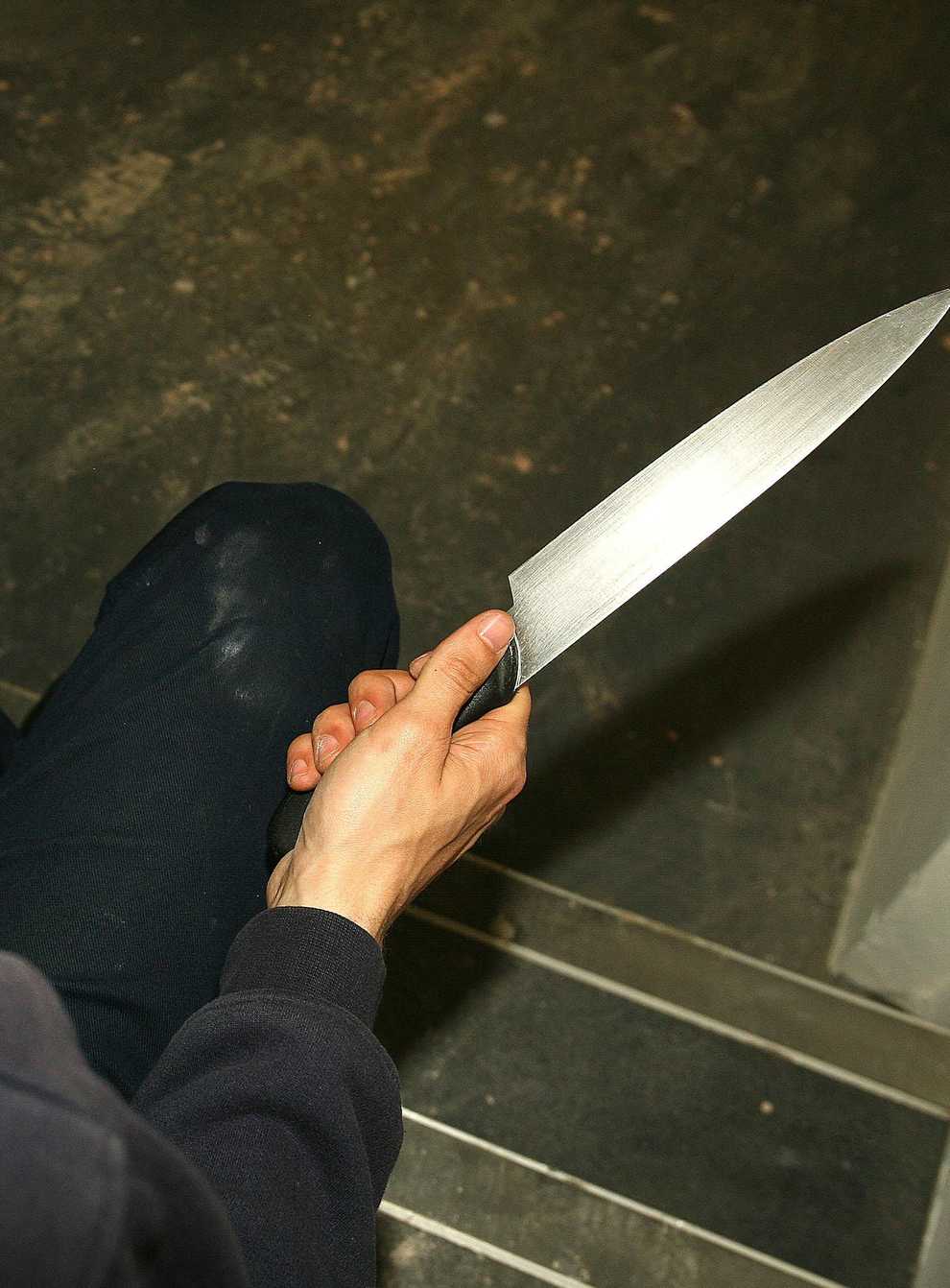 File photo of a man in a hoodie holding a knife. (Katie Collins/PA)