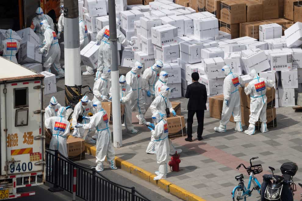 Workers unload supplies including boxes of masks in Shanghai (Chinatopix via AP)