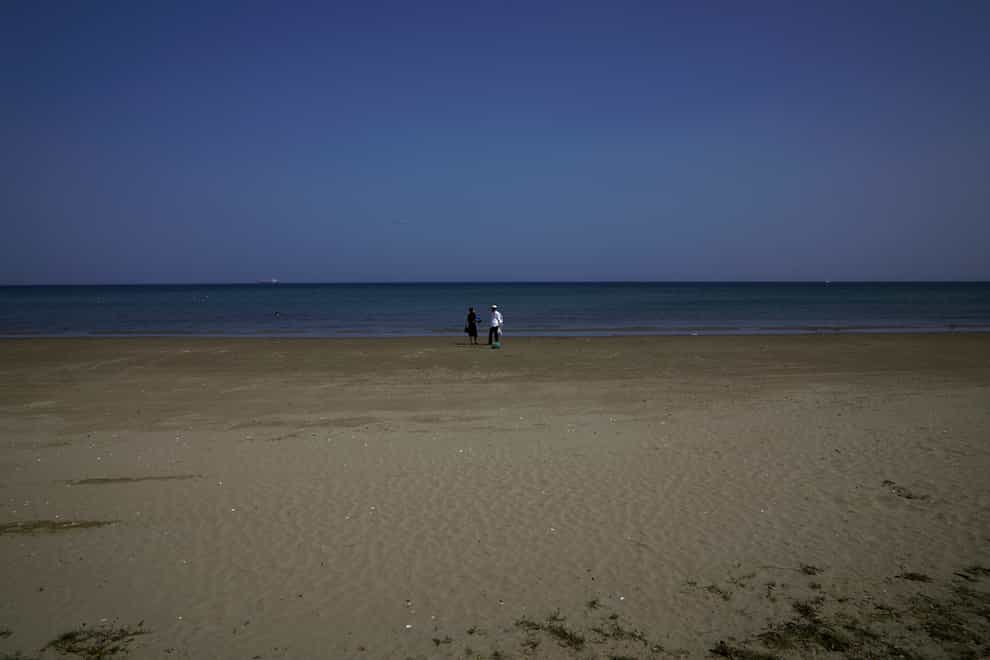 A couple walk on the beach in the southern coastal city of Larnaca (Petros Karadjias/AP)