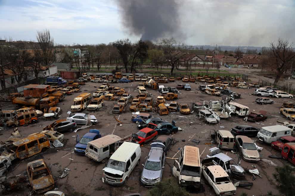 Damaged and burned vehicles are seen at a destroyed part of the Illich Iron & Steel Works Metallurgical Plant, as smoke rises from the Metallurgical Combine Azovstal during heavy fighting in an area controlled by Russian-backed separatist forces in Mariupol, Ukraine, on Monday April 18 2022 (Alexei Alexandrov/AP)