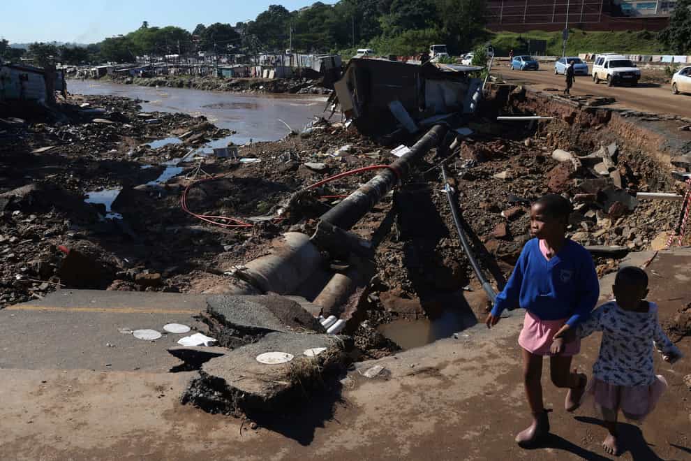 Children walk on damaged road at an informal settlement in Durban, South Africa, Thursday, April 14, 2022. Heavy rains and flooding have killed at least 341 people in South Africa’s eastern KwaZulu-Natal province, including the city of Durban, and more rainstorms are forecast in the coming days. (AP Photo/Str)