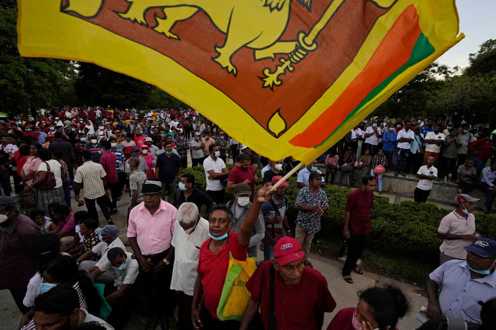A member of Sri Lanka’s opposition political party National People’s Power waves country’s national flag as he participates in an anti-government protest rally in Colombo, Sri Lanka, Tuesday, April 19, 2022. Sri Lanka’s prime minister said Tuesday the constitution will be changed to clip presidential powers and empower Parliament as protesters continued to call on the president and his powerful family to quit over the country’s economic crisis. (AP Photo/Eranga Jayawardena)