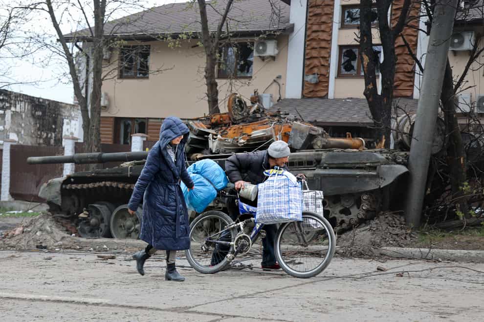 Local civilians walk past a tank destroyed during heavy fighting in an area controlled by Russian-backed separatist forces in Mariupol, Ukraine (Alexei Alexandrov/AP)