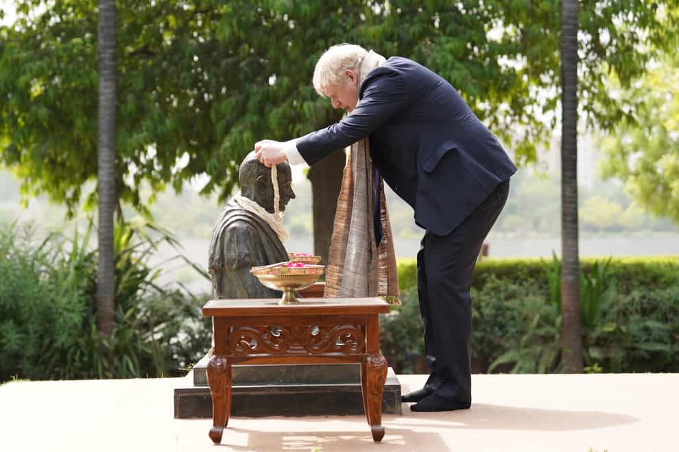 Prime Minister Boris Johnson places a garland around the neck of a statue of Mahatma Gandhi (Stefan Rousseau/PA)