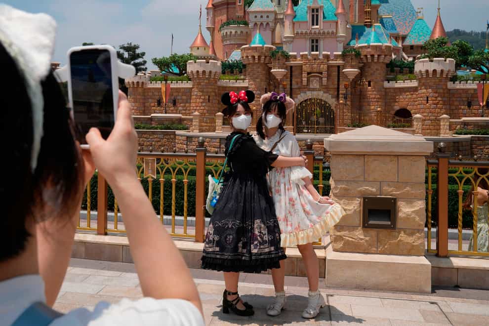 Visitors wearing face masks take photos at the Hong Kong Disneyland (AP)
