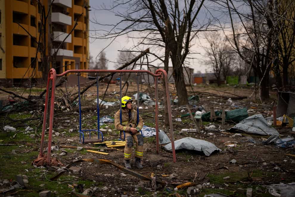 A firefighter sits on a swing next to a building destroyed by a Russian bomb in Chernihiv (Emilio Morenatti/AP)