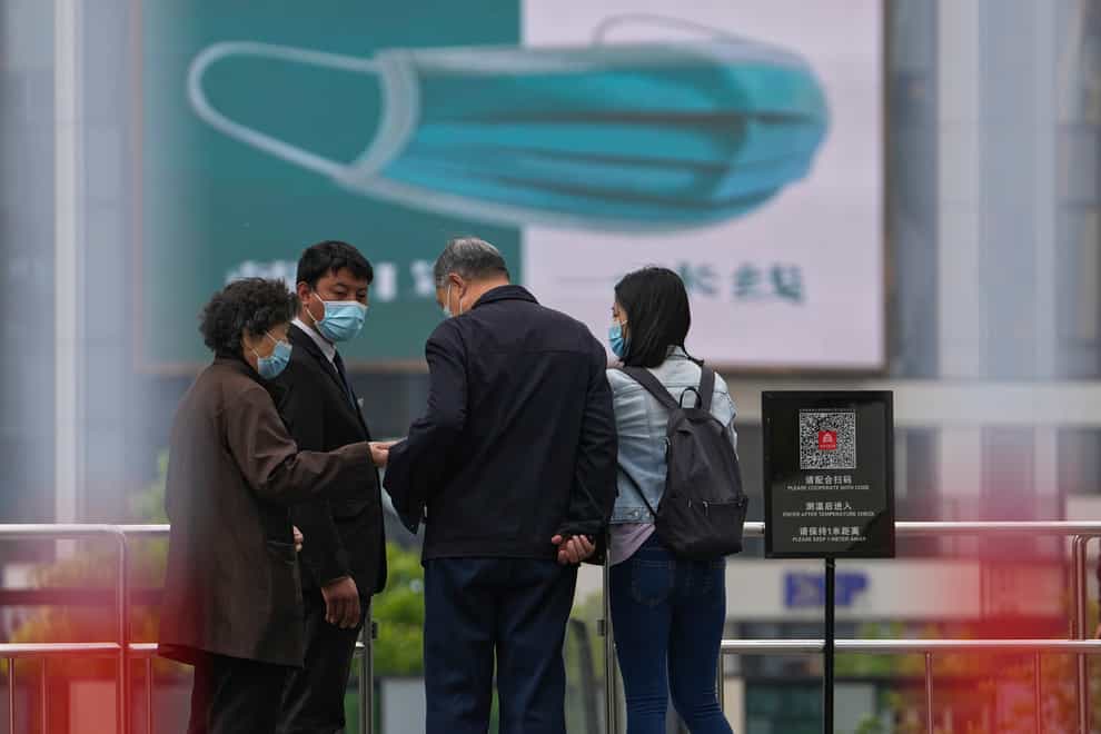 A security guard wearing a face mask stands watch as masked residents use their smartphone to scan their health code at a barricaded entrance to a commercial office complex in Beijing (AP Photo/Andy Wong)
