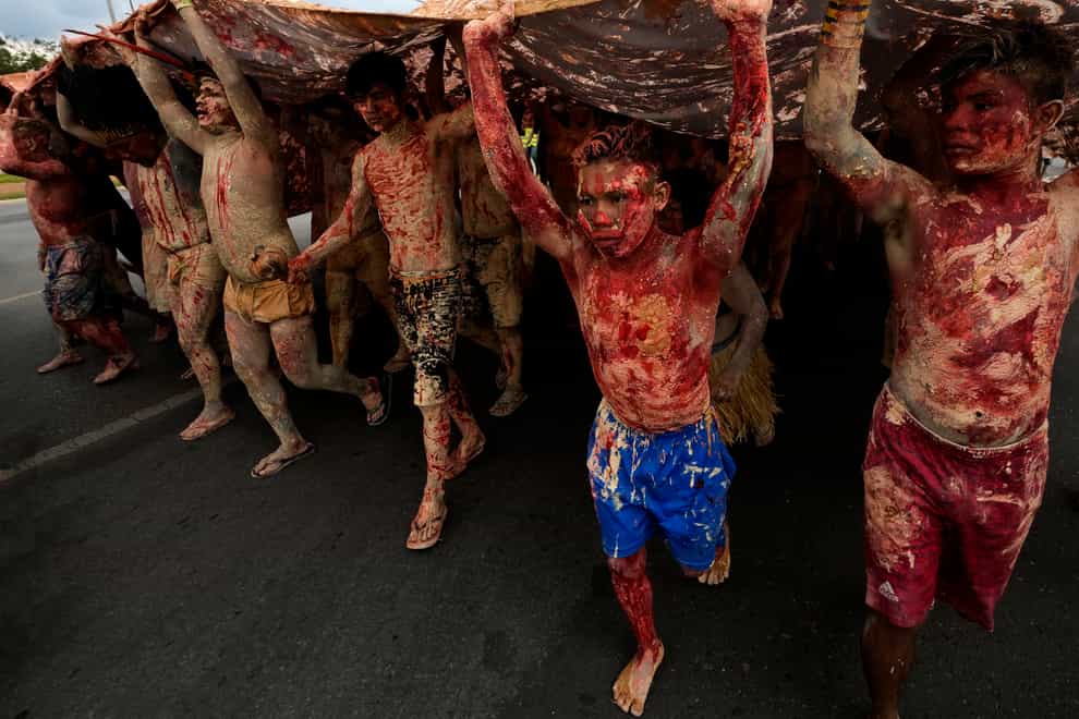 Indigenous people, painted with red ink representing spilled indigenous blood and clay representing gold, march during a protest against the increase of mining activities that are encroaching on their land, in front of the Ministry of Mines and Energy in Brazil (Eraldo Peres/AP)