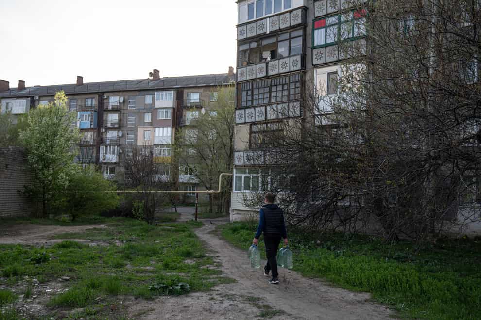 Andriy Cheremushkin carries cans with water in Toretsk, eastern Ukraine (Evgeniy Maloletka/AP)