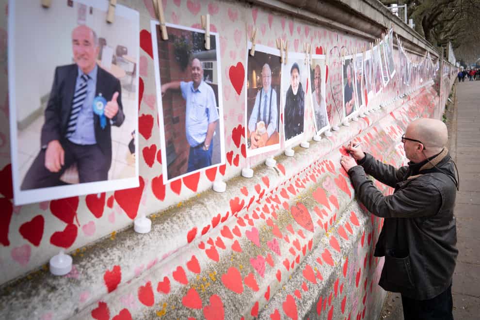 A family member pays their respects to those who lost their lives to coronavirus at the Covid memorial wall in central London (Stefan Rousseau/PA)