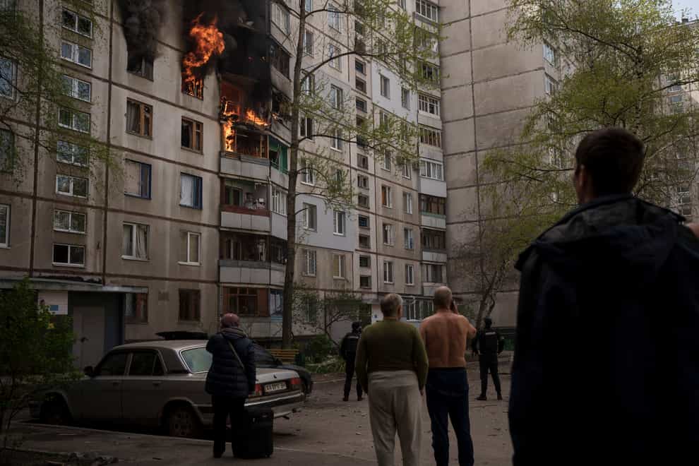 People watch as a residential building burns following a Russian bombardment in Kharkiv, Ukraine (Felipe Dana/AP)