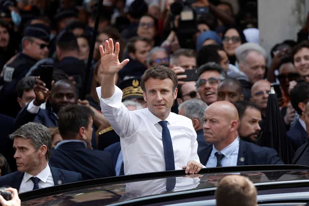 Newly re-elected French President Emmanuel Macron waves from his car after his visit at the Saint-Christophe market square in Cergy, a Paris suburb (Benoit Tessier, Pool via AP)