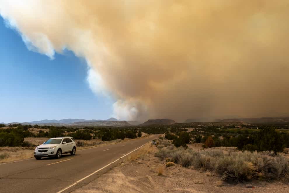 A vehicle heads away from a plume of smoke from the Cerro Pelado Fire burning in the Jemez Mountains , New Mexico (The Albuquerque Journal via AP)