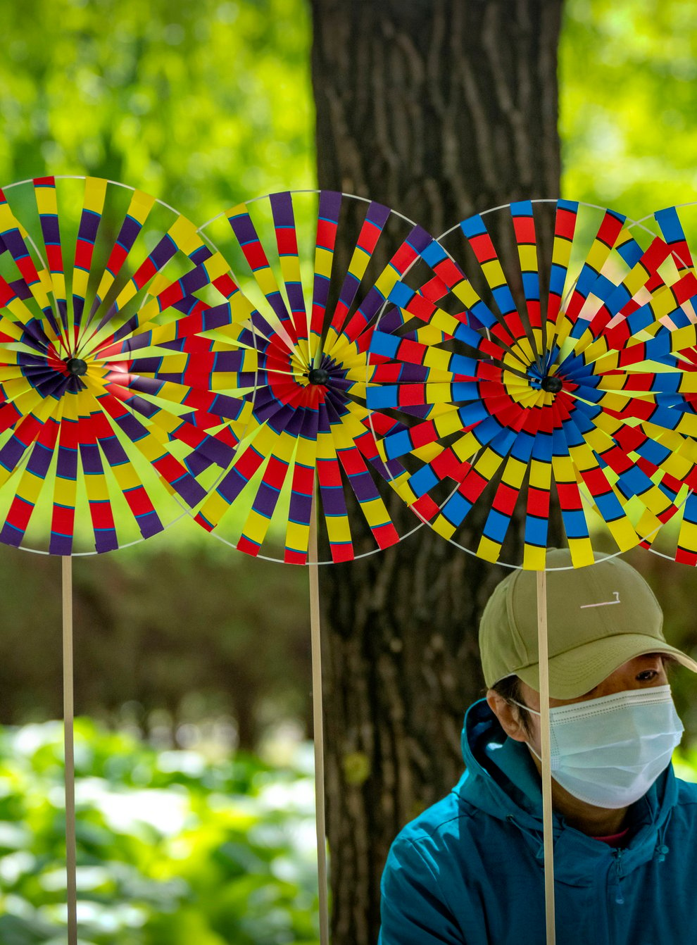 A vendor wearing a face mask sits near pinwheels for sale at a public park in Beijing (Mark Schiefelbein/AP)