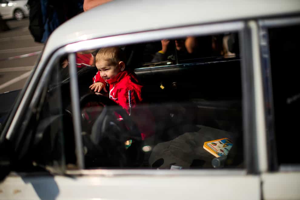 A child looks through a car windscreen as his family waits to be processed upon their arrival from Vasylivka at a reception centre for displaced people in Zaporizhzhia, Ukraine (Francisco Seco/AP)
