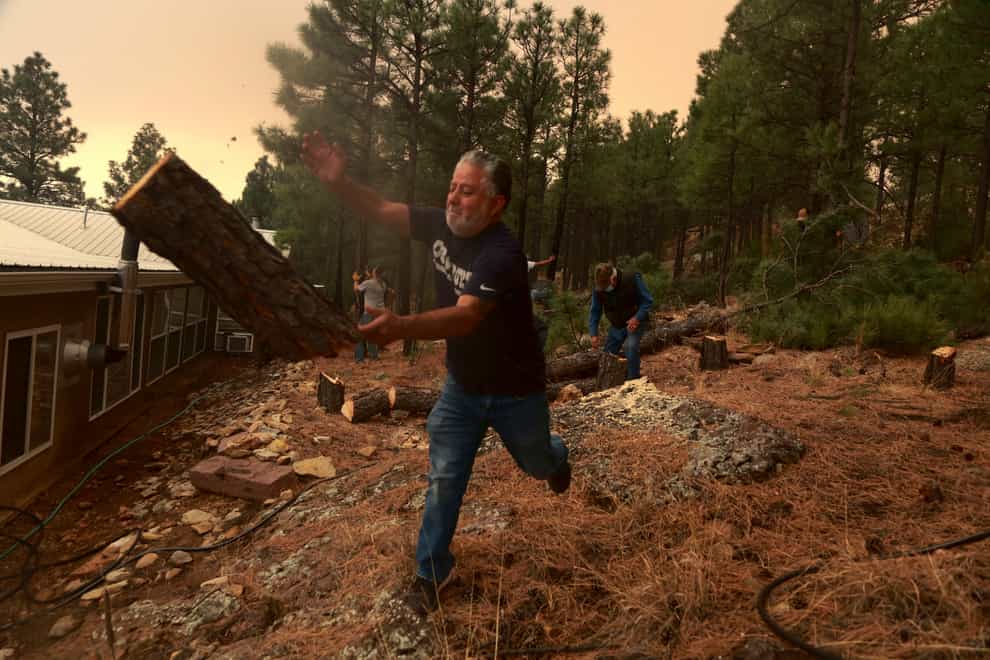 Chris Castillo throws a freshly-cut log as he and his cousins clear a wireline along a family member’s home in Las Vegas, New Mexico, on Monday May 2 2022 (Cedar Attanasio/AP)